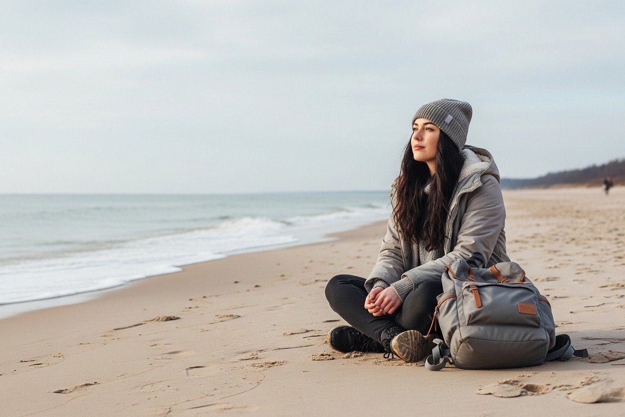 each, woman, backpack, sea, ocean, sand, travel, nature, coast, shoreline, holiday, vacation, outdoor, peaceful, serene, horizon, sitting, solitude, relaxation, cold weather, winter beach, adventure, wanderlust, exploration, scenic